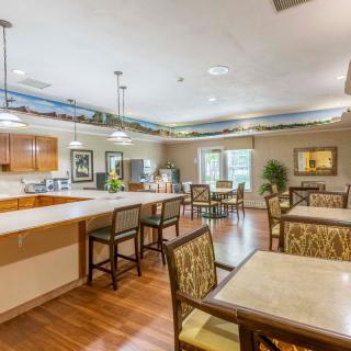 A cozy dining area with a kitchen, featuring wooden floors and comfortable seating.