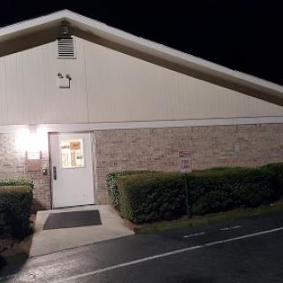 A well-lit building entrance at night, showcasing brick and landscaping.