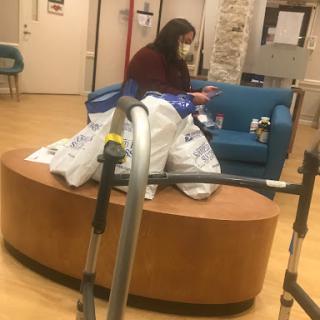A person sitting in a waiting area surrounded by bags, wearing a mask.