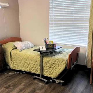 A hospital patient room with a bed and bedside table.