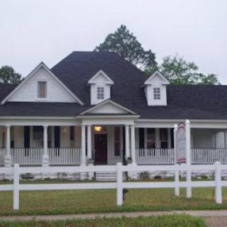 A charming suburban house with a large porch and white fence.