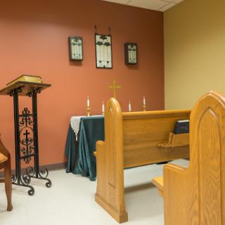 A serene chapel setting featuring wooden pews and a podium, designed for quiet reflection and prayer.