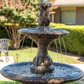 A decorative garden fountain with flowing water surrounded by greenery.
