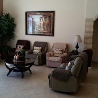 A cozy living room with multiple recliners, a coffee table, artwork on the wall, and an indoor plant.