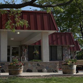 A modern building with a red roof, surrounded by greenery and decorative planters.