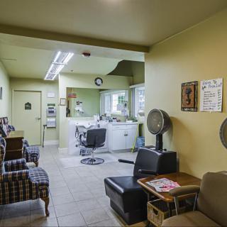 A cozy barbershop interior with a waiting area, hair styling station, and classic salon chairs.