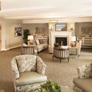 A cozy and elegantly furnished living room with sofas, armchairs, a coffee table, and a fireplace.