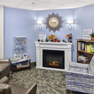 A cozy living room with a fireplace, armchairs, and decorative elements.