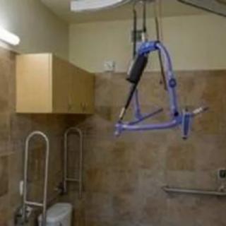 An accessible bathroom equipped with a ceiling lift system for mobility assistance.