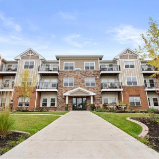 A modern residential apartment building with a welcoming entrance and landscaped surroundings.