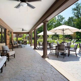 A spacious outdoor patio with comfortable seating and umbrellas overlooking a garden.