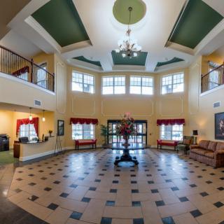 A spacious lobby with a chandelier, large windows, and comfortable seating.