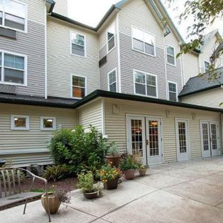 A multi-story residential building with a patio area and potted plants.