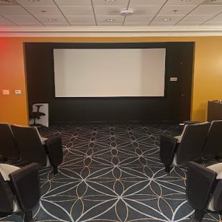 A modern cinema room featuring a screen and comfortable seating.