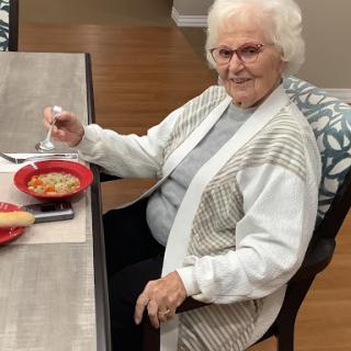 An elderly woman enjoying a meal at the table.