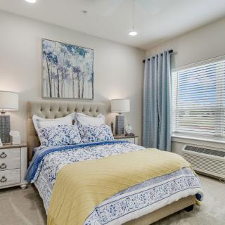A cozy bedroom with elegant decor, featuring a neatly made bed with patterned bedding and soft lighting from bedside lamps.