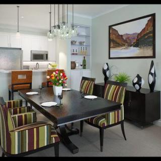 A modern dining room with striped chairs, a dark wooden table, and elegant pendant lighting.