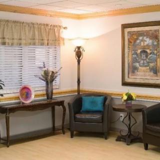 A cozy living room corner with armchairs, a decorative table, and a framed painting.