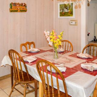 A cozy dining room with a table set for four, featuring a vase of flowers and an inviting atmosphere.