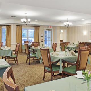 A well-lit dining area with green tablecloths and neatly arranged tables and chairs.