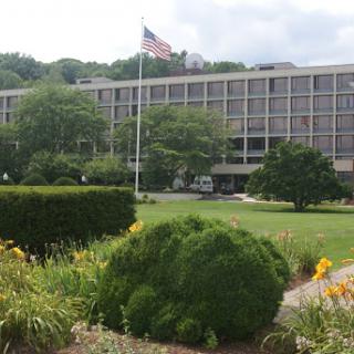 A view of a modern building with an American flag and landscaped gardens.