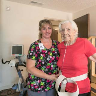 An elderly person with a caregiver in a healthcare setting.