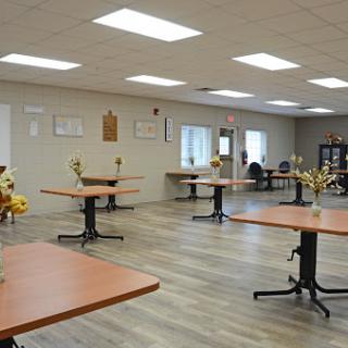 A spacious and well-lit event room set up with tables and decorative flowers.