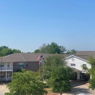 A residential building with flags and trees under a clear blue sky.