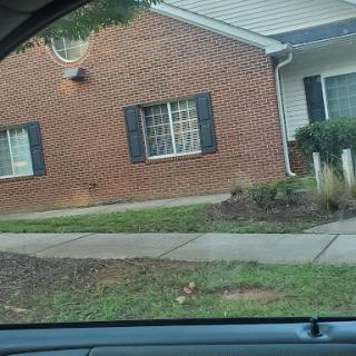 A view of a brick residential building with windows and landscaped front yard.