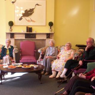A group of seniors sitting together in a cozy living room, enjoying each other's company.