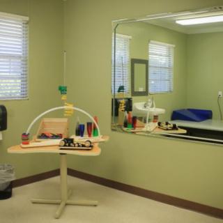 A therapy room equipped with tools for rehabilitation exercises, featuring a large mirror and various therapeutic equipment.