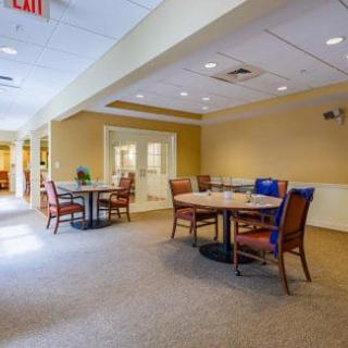 A cozy dining area with several tables and chairs arranged on a carpeted floor.