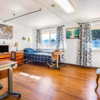 A spacious and well-lit hospital room with a bed, desk, and windows.