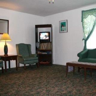A cozy living room with classic furniture, including a lamp, chairs, and a television.