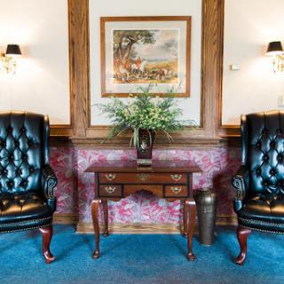A cozy and elegant living area featuring plush armchairs, a decorative table, and a piece of artwork on the wall.