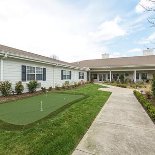 A view of a single-story building with a well-maintained lawn and a concrete pathway leading to the entrance.