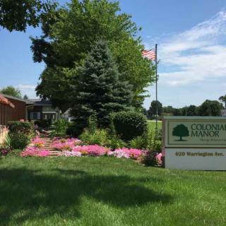 A beautifully landscaped garden with blooming flowers and lush greenery, featuring a sign for Old Town Bluffton.
