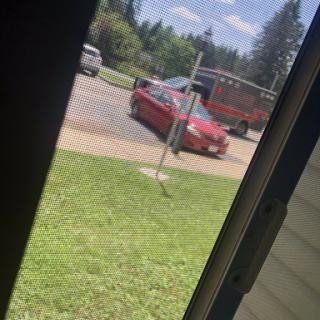 A red car parked in a lot on a sunny day.
