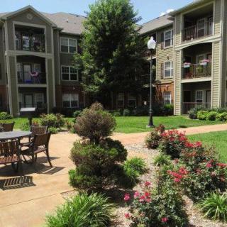 A well-maintained apartment complex with lush landscaping and outdoor seating.