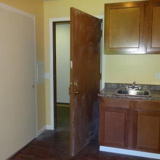 Small kitchen area with wooden cabinets and an open door.