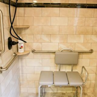 An accessible shower equipped with a seat and grab bars for safety.