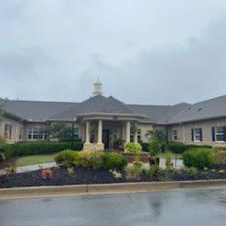 A large suburban house on a rainy day with a well-maintained garden.