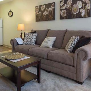 A cozy living room featuring a brown sofa with decorative pillows, a wooden coffee table, and wall art.