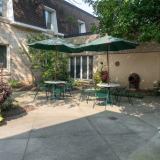 A peaceful outdoor patio area featuring tables with umbrellas, perfect for relaxation and enjoying the garden.