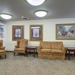 A cozy waiting area with patterned chairs, a sofa, and framed artwork on the walls.