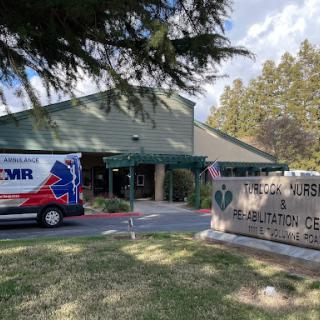 A medical center with an ambulance parked outside, surrounded by trees.