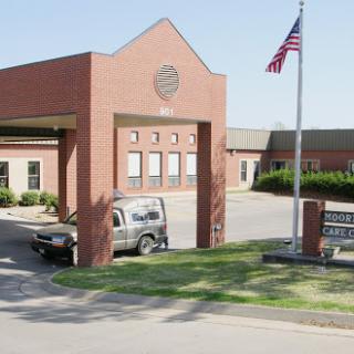 A view of the entrance to a brick building featuring an American flag and a parked vehicle.