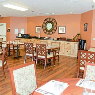 A cozy dining room with wooden floors and neatly arranged tables and chairs.