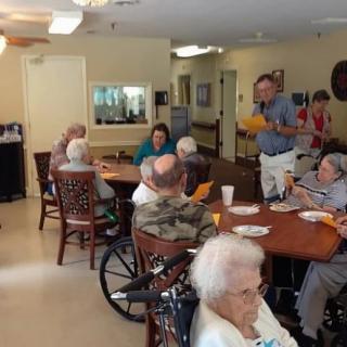 Elderly residents gather in a community room for activities at a nursing home.
