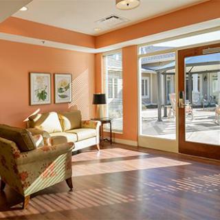 A cozy living room bathed in sunlight, featuring comfortable seating and large windows.